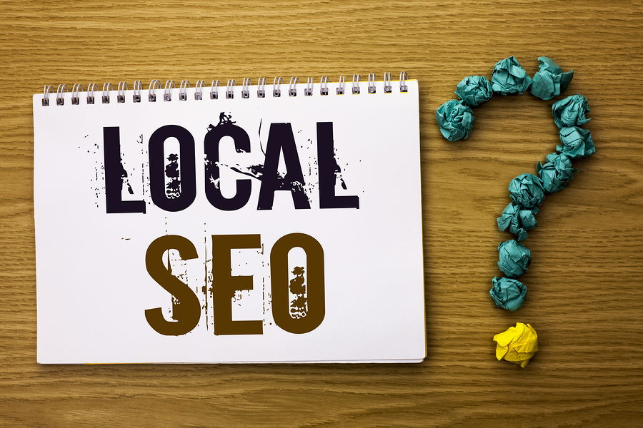 The words local seo written on a pad o fpaper with a question mark made from marbles next to it